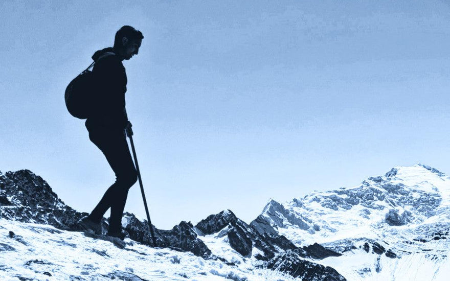 man in black alpaca wool clothing walking down a snowy slope