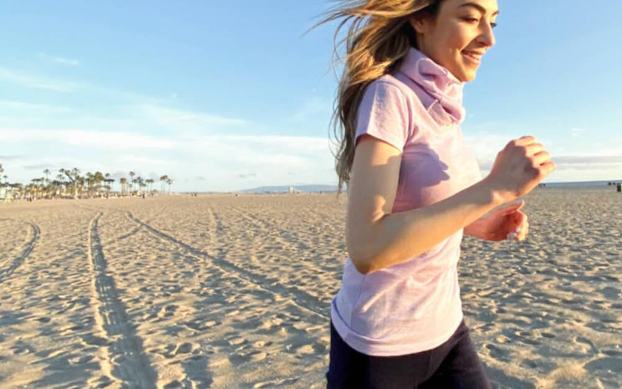 woman running on a beach wearing alpaca wool shirt and alpaca leggings