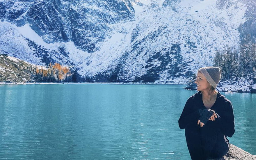 Woman wearing alpaca wool clothing near glacier lake