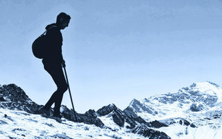 man in black alpaca wool clothing walking down a snowy slope