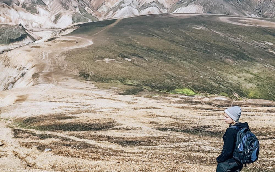 woman wearing and alpaca sweater and backback looking over mountains