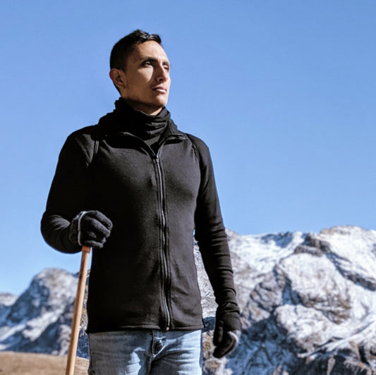 man wearing black full zip alpaca base layer with mountains in the background
