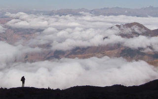 silhouette of a person backpacking above the clouds