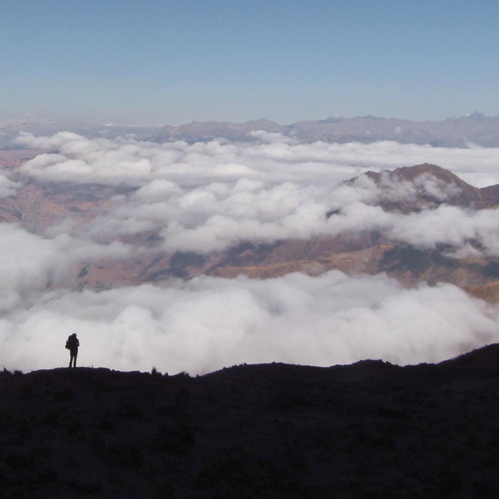 silhouette of a person backpacking above the clouds