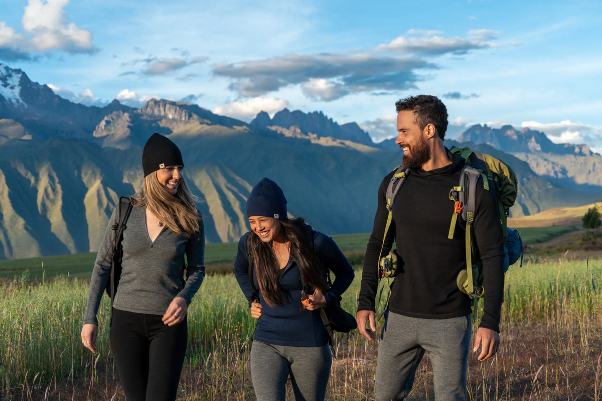 Three hikers in Alpaca base layers walking through highland grass with the Andes behind them