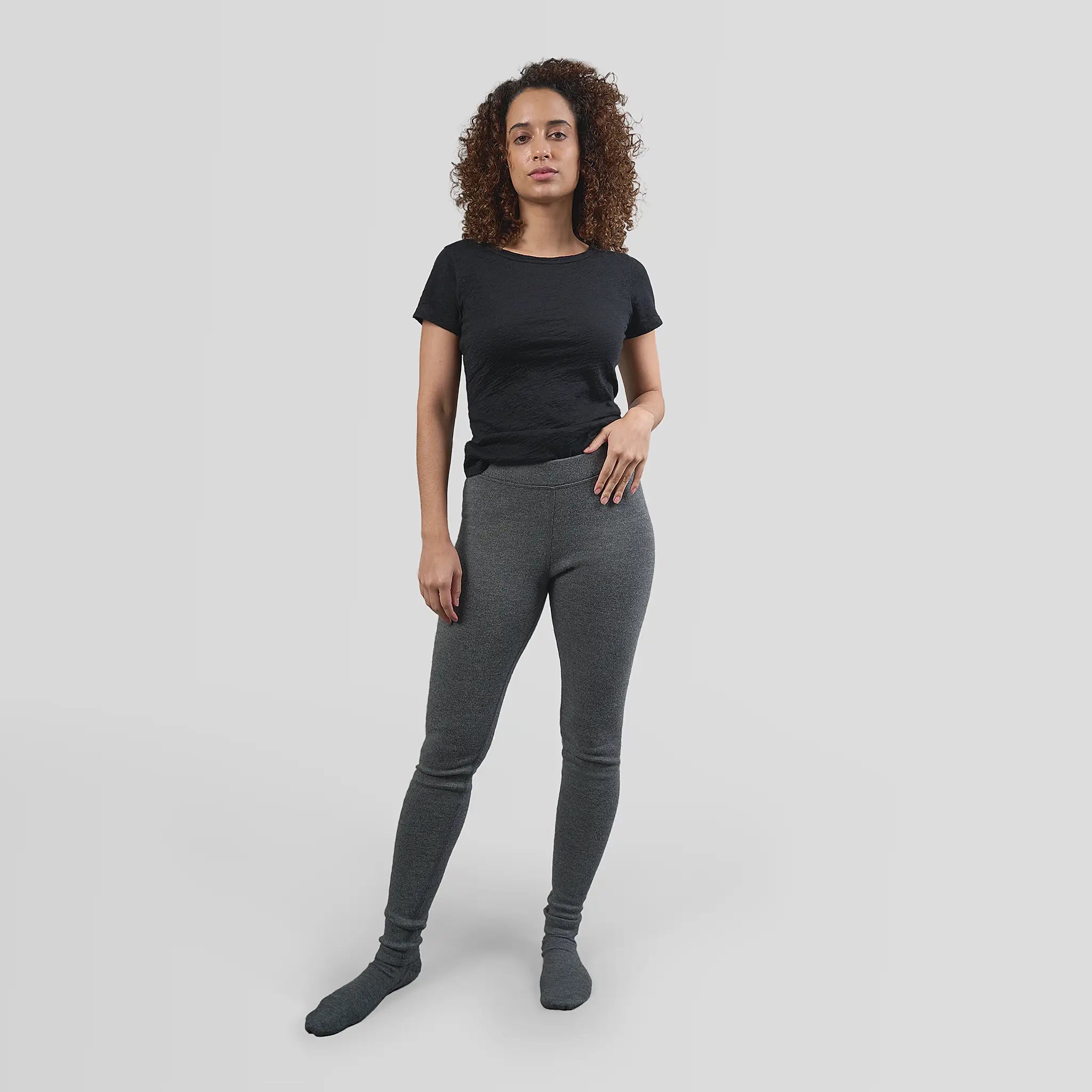 Premium Photo  A woman puts on warm gray woolen leggings, women's legs in  winter leggings